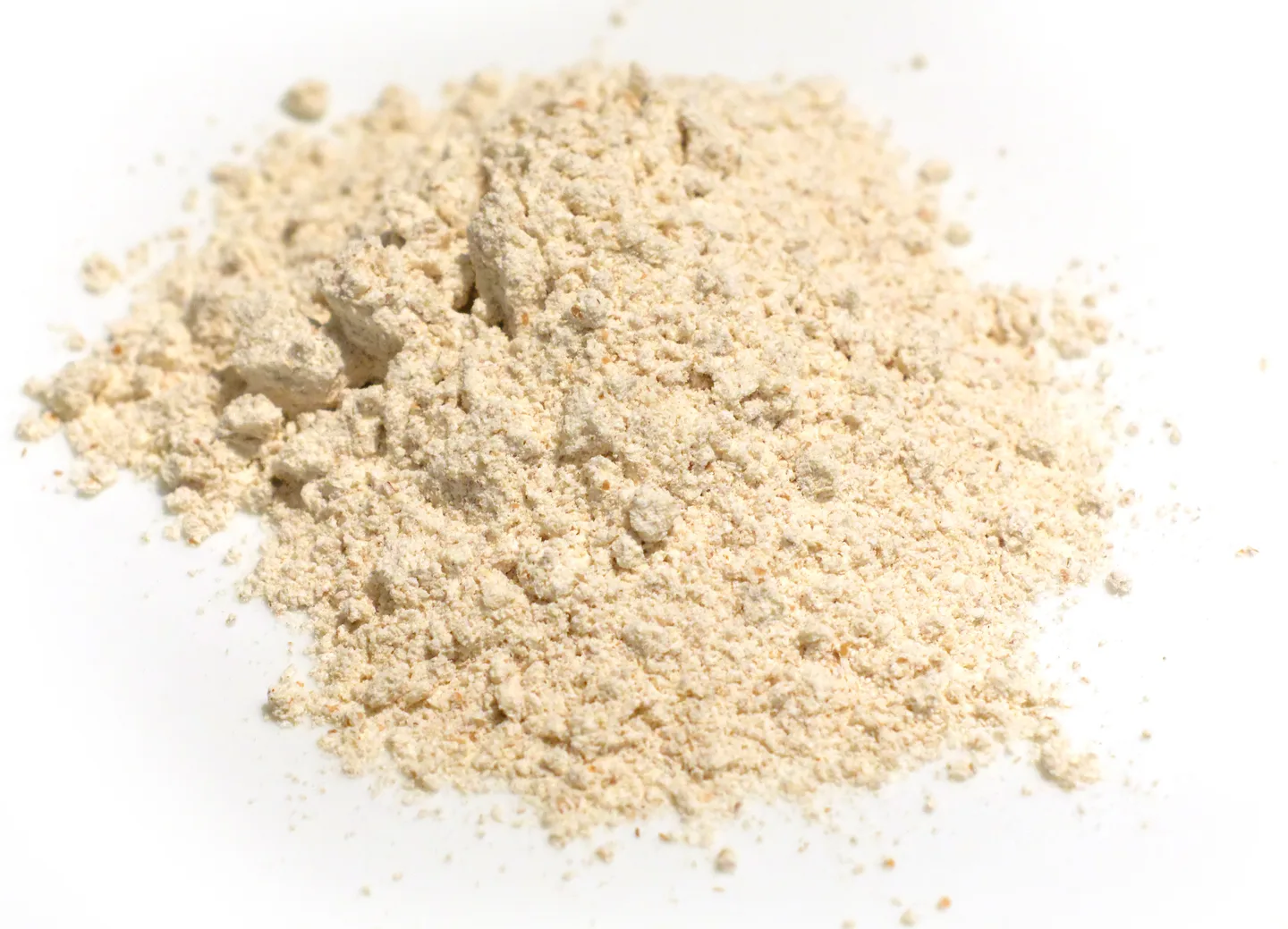 A mound of pale beige wholemeal spelt flour on a white surface